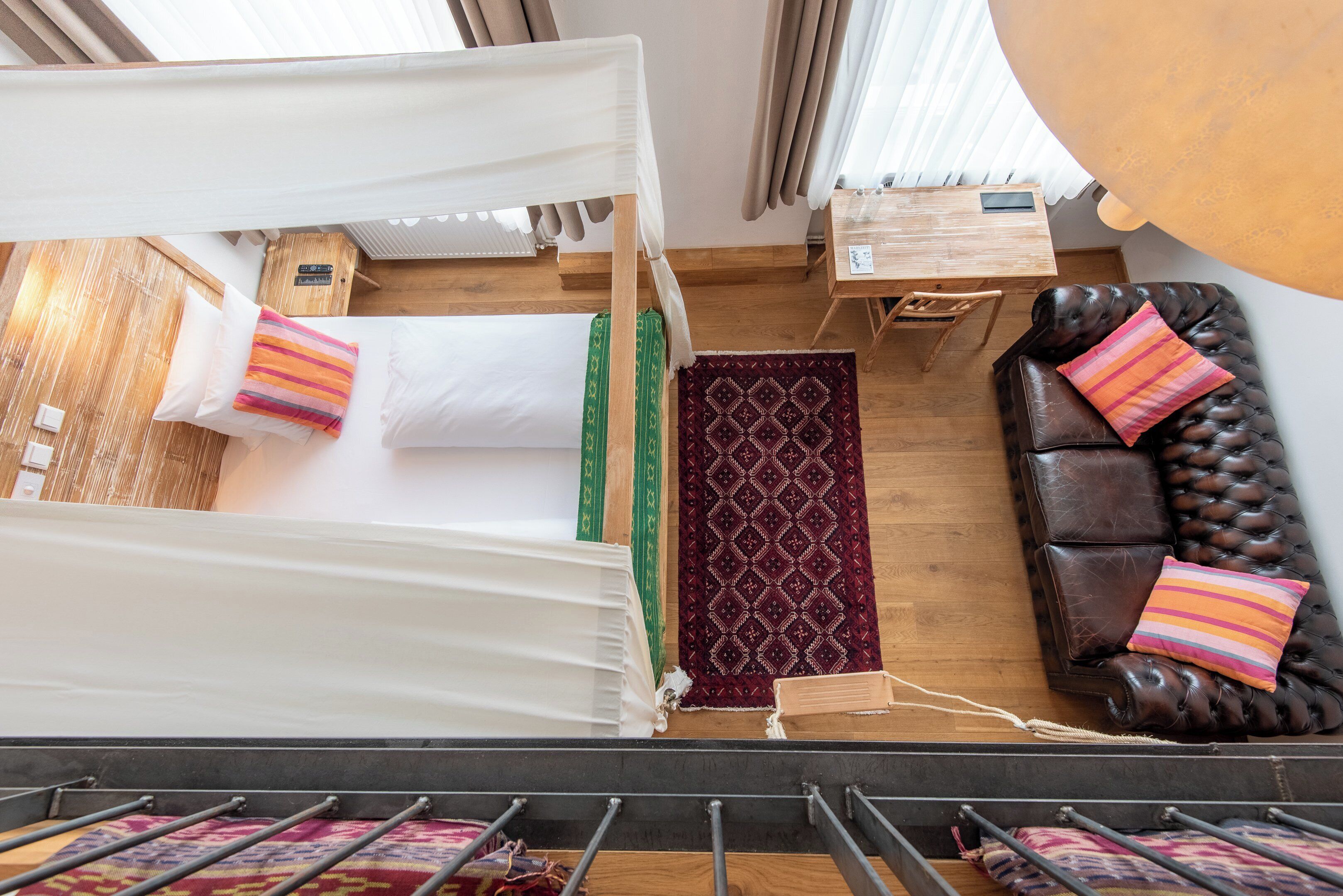 Une pièce comprenant un lit, une table en bois, un canapé en cuir et un tapis à motifs.