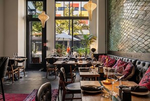 Un espace de restauration intérieur comprenant plusieurs tables, des chaises et un coin salon avec des coussins.