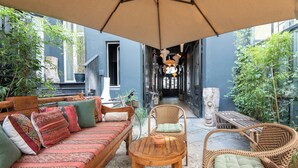 Un rincón exterior acogedor con un sofá, sillas y una mesa bajo un gran paraguas.