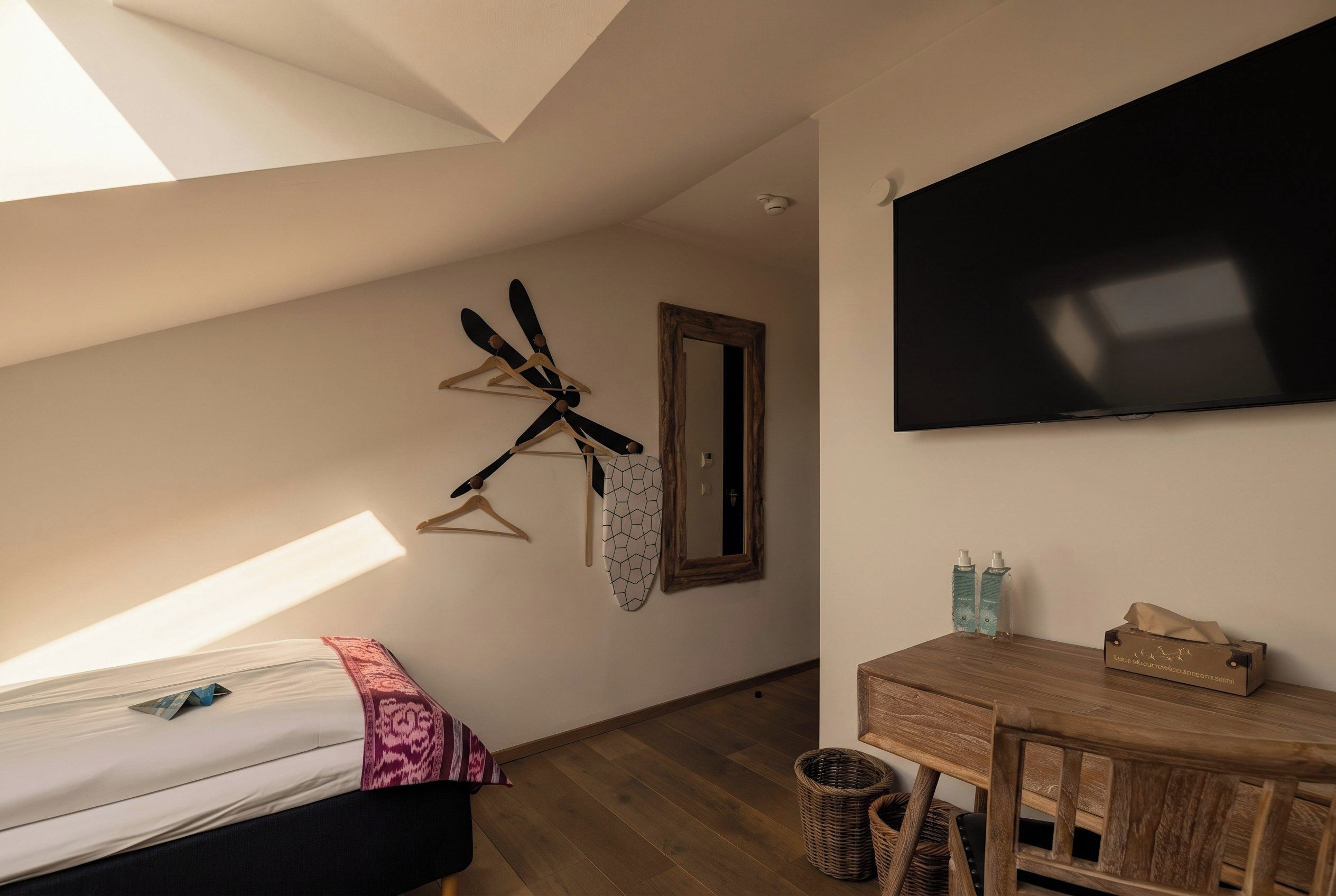 Une chambre à coucher avec un lit, un bureau, un miroir et une télévision.