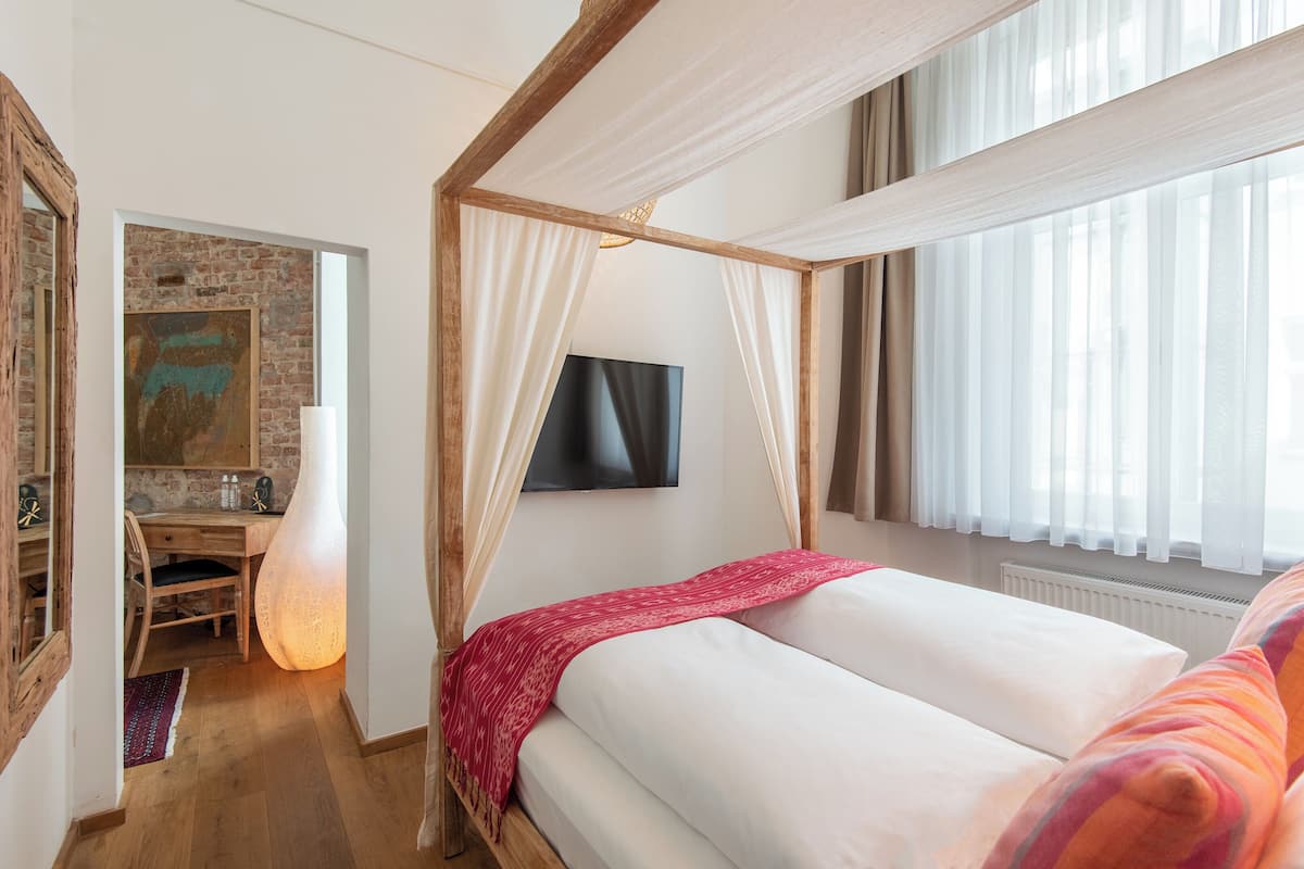 Une chambre à coucher avec un lit à baldaquin, un bureau et un téléviseur.