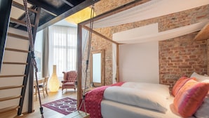 Un dormitorio con cama de madera, un columpio, una escalera y una pared de ladrillo.