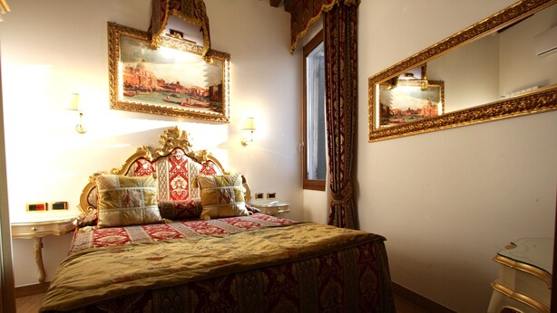 A bedroom with a large bed, ornate headboard, two bedside tables, a mirror, and a window with curtains. - Splendid Star..... San Mark's Square all inclusive WiFi (Venezia)