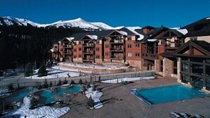 Ein Resort mit mehreren Gebäuden, einem Schwimmbad und verschneiten Bergen im Hintergrund.