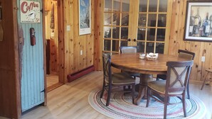 Ein Holzinterieur mit einem Esstisch, Stühlen, einer Kaffeemaschine und einer Tür mit einem Schild.