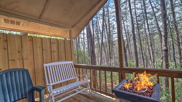 A wooden deck with a bench and a stone fire pit.