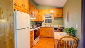 A compact kitchen with wooden cabinets, a refrigerator, a microwave, and a sink.
