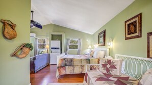 A cozy bedroom with a bed, a sofa, and a small kitchenette.