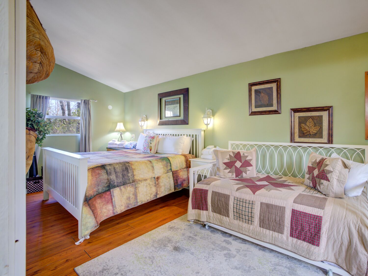 A bedroom with two beds, a radiator, a window with curtains, and wall-mounted lamps.