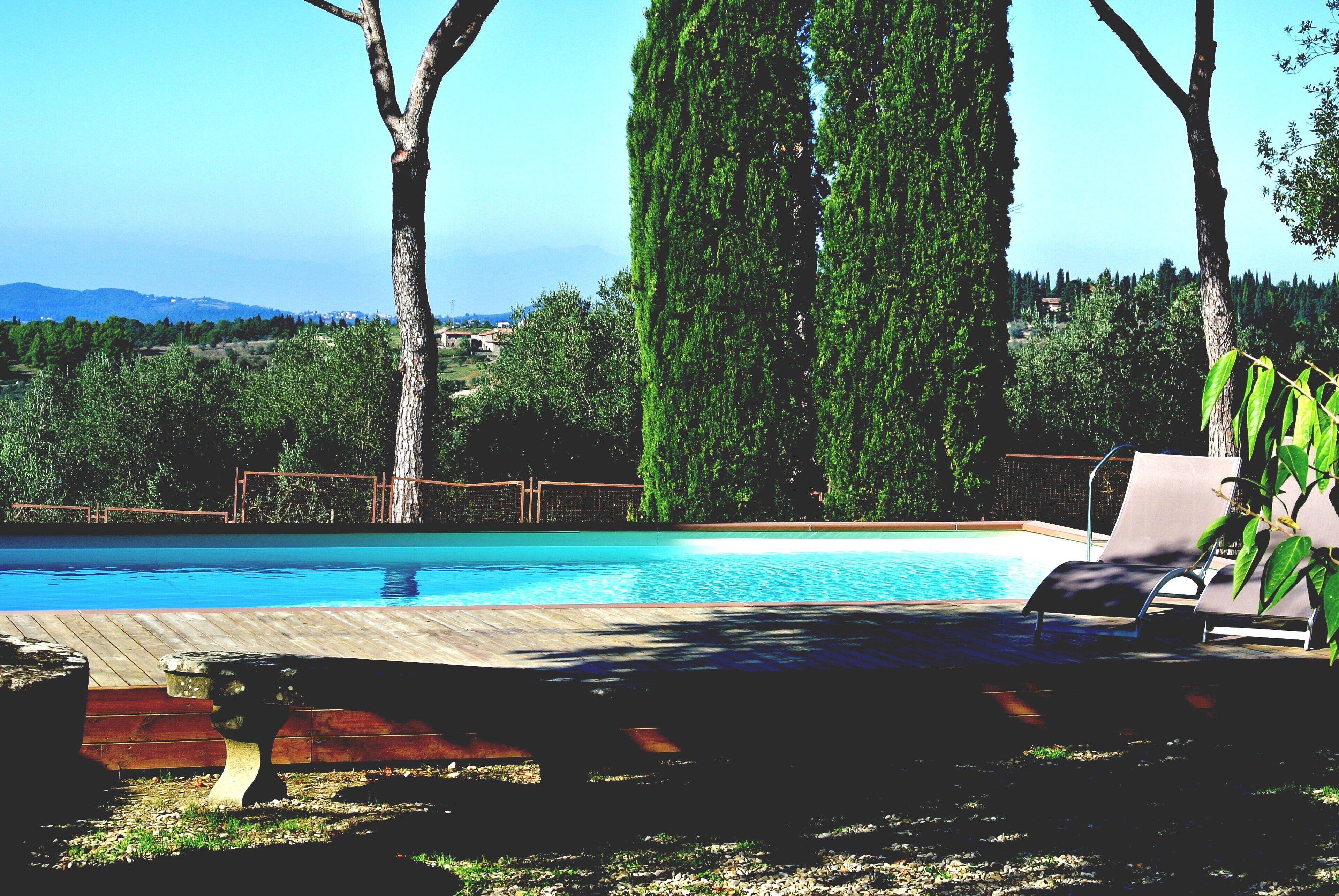 A swimming pool with lounge chairs and a wooden deck.