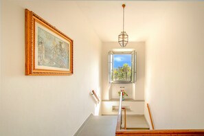 A staircase with a view of a garden through a window, a framed painting on the wall, and a hanging light fixture. - Authentic Private Tuscan Villa for 12 people in Greve: the Heart of Chianti (Greve in Chianti (Firenze))