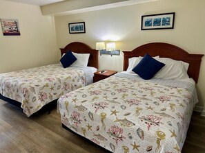 Two adjacent beds with matching headboards, a nightstand between them, and wall-mounted lamps. - "Direct" Ocean Front 9th Floor cozy coastal cottage Reasonable Rates (Myrtle Beach)