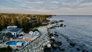 A coastal property with a swimming pool, a large house, and a view of the sea. - Relaxing Oceanfront Retreat . Hot tub -sauna-pool-clear domes-private (South Shore)