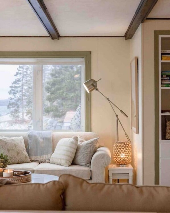 A cozy living room with a sofa, a side table with a lamp, and a bookshelf. - Relaxing Oceanfront Retreat . Hot tub -sauna-pool-clear domes-private (South Shore)
