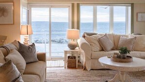 A cozy living room with a large window overlooking the sea, a sofa, a coffee table, and a lamp. - Relaxing Oceanfront Retreat . Hot tub -sauna-pool-clear domes-private (South Shore)