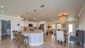 A spacious kitchen with a central island, dining area with chairs, and a chandelier. - 841 Vanderbilt Beach Bliss • Lux Waterfront Home (Naples)