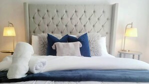 A neatly made bed with a tufted headboard, white and blue pillows, and a white towel. - 841 Vanderbilt Beach Bliss • Lux Waterfront Home (Naples)