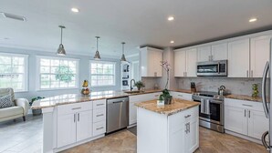 A modern kitchen with white cabinets, granite countertops, stainless steel appliances, and pendant lighting. - 841 Vanderbilt Beach Bliss • Lux Waterfront Home (Naples)