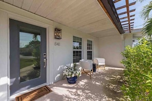 A covered porch with a door, a number '841' above it, a potted plant, and a bench.