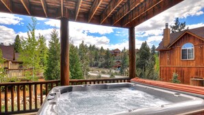 A hot tub on a wooden deck with a view of a forest and houses. - Castle Glen Dream Estate! Spa, movie theater, lake and mountain views! (Big Bear)