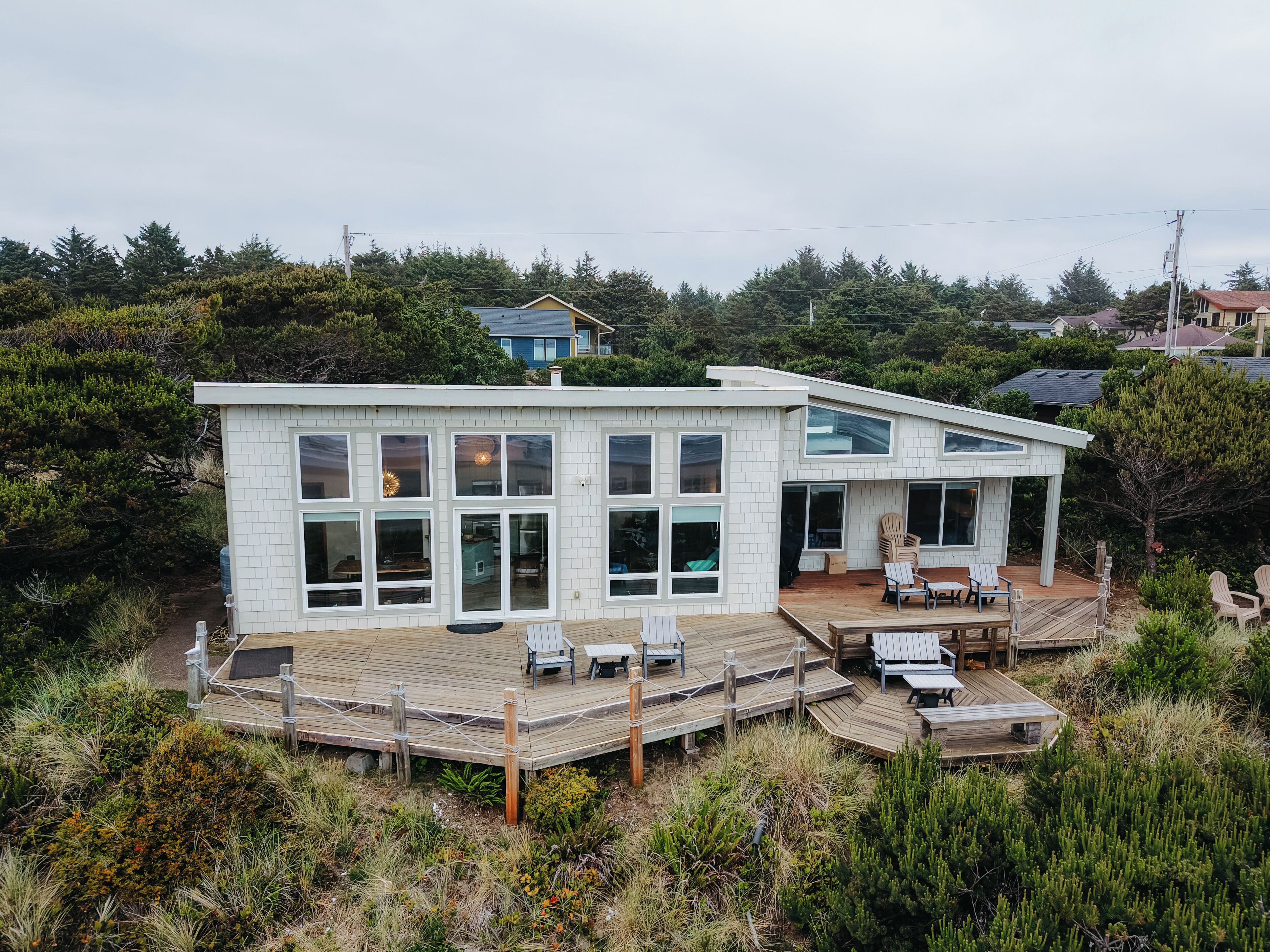 Una casa moderna de dos pisos con terraza, ventanas amplias y vista al paisaje circundante.
