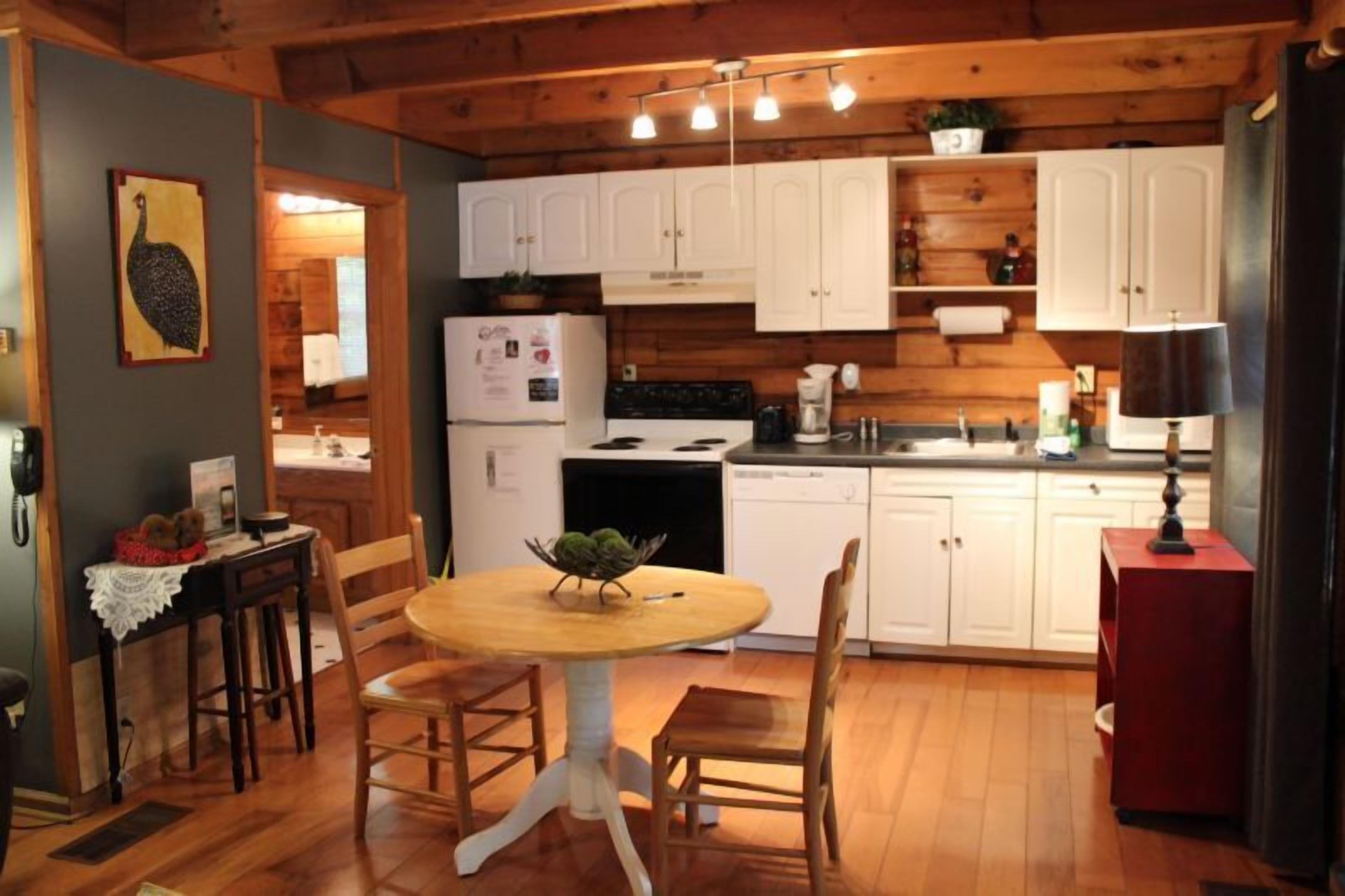 A cozy kitchen with wooden cabinets, a stove, and a dining area with a table and chairs.
