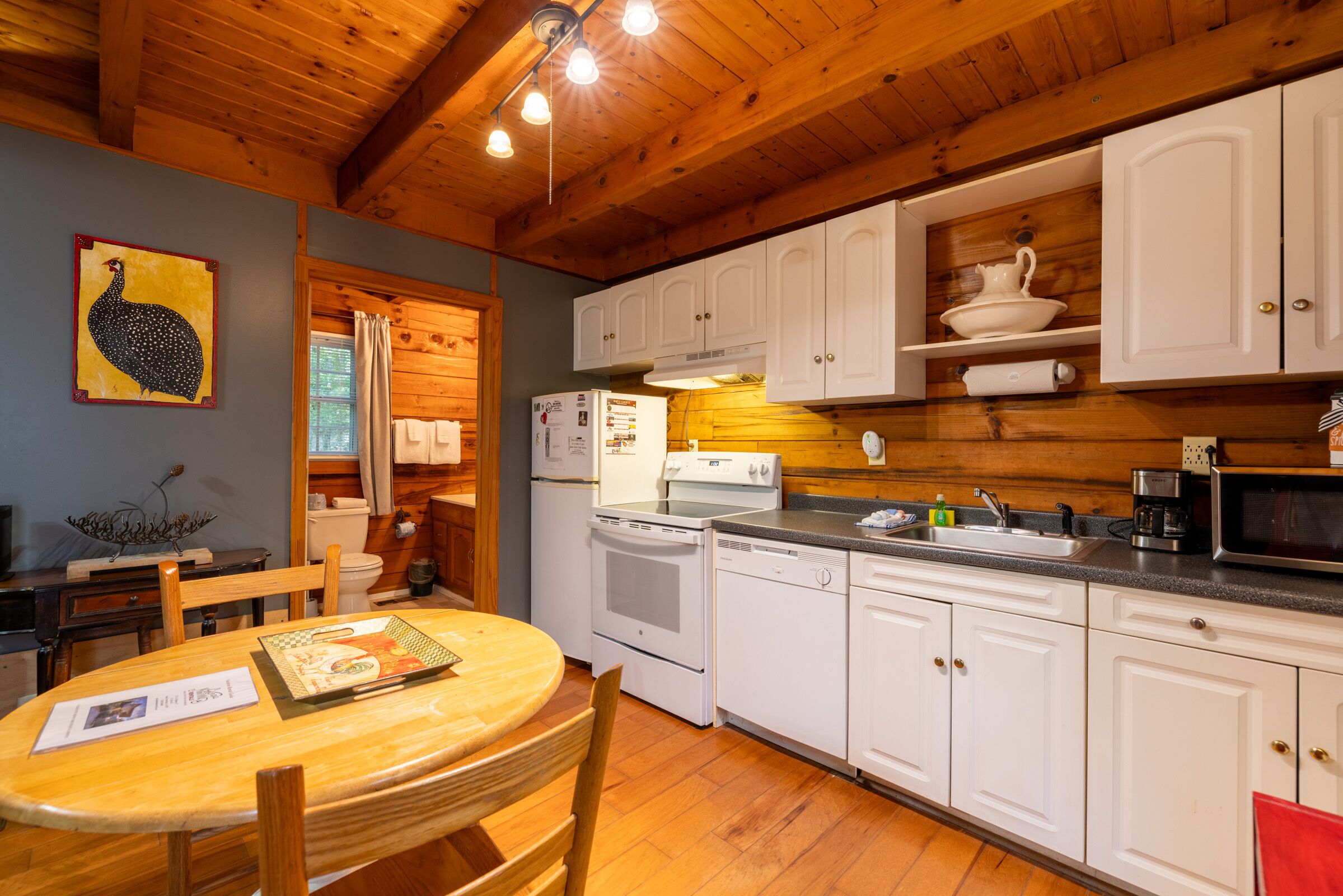 Une cuisine avec des meubles de rangement en bois, un évier, une cuisinière et une table à manger avec des chaises.