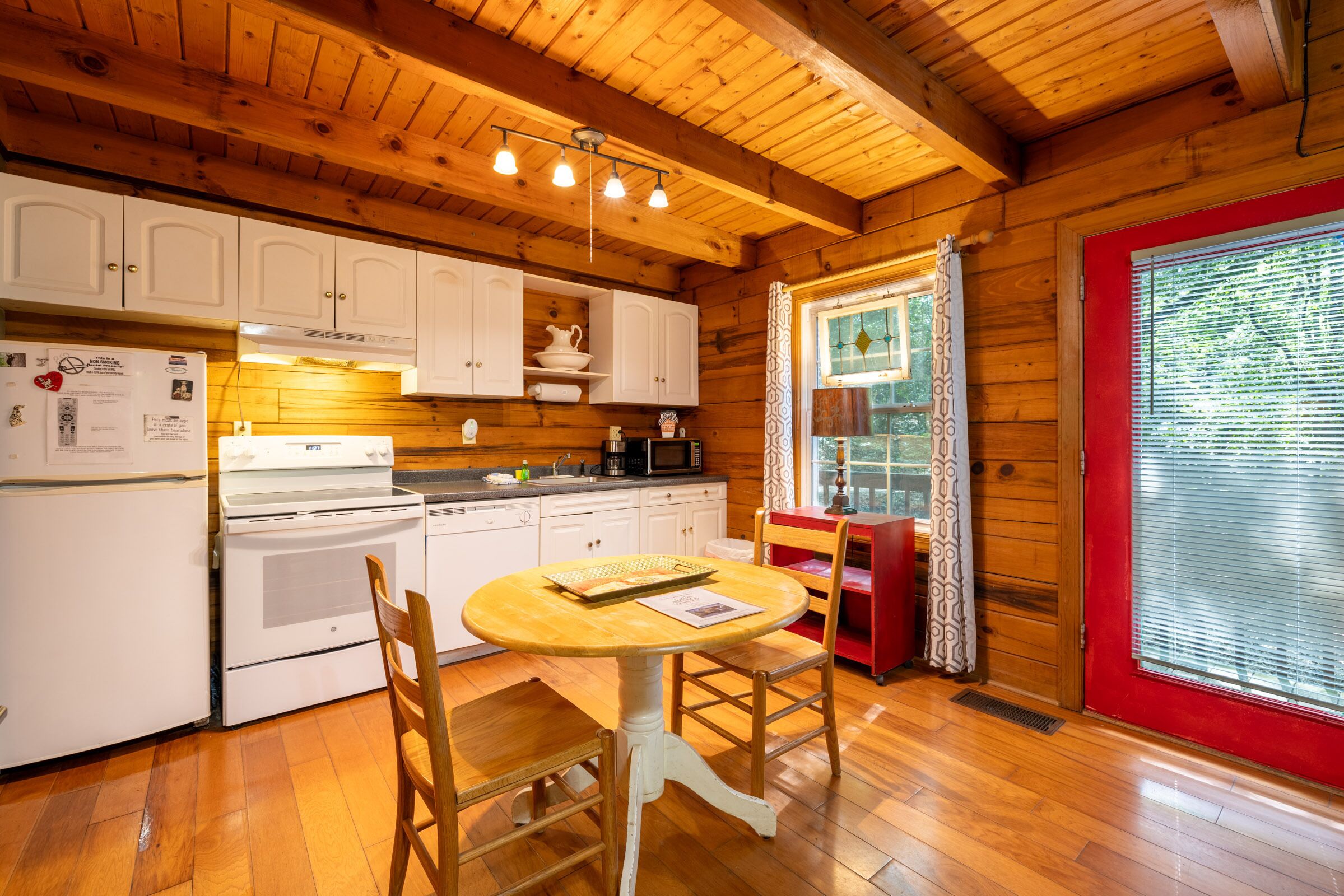 A wooden cabin interior with a kitchen, dining table, and chairs.