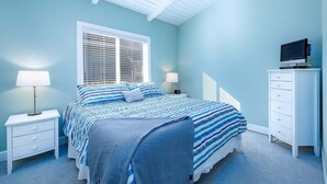 A bedroom with a bed, nightstands, a dresser, a television, and a window with blinds.