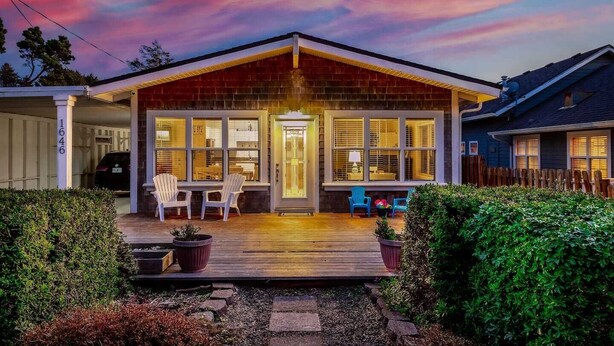 A house with a wooden deck, a covered porch, and a garage.