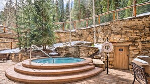 A stone-walled pool area with a wooden deck, a lifebuoy, and a sign indicating no glass allowed.