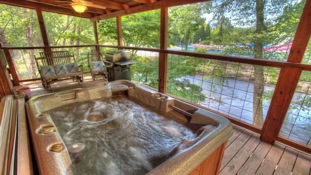 Ein Whirlpool mit einer Holzterrasse und Blick auf einen Park.