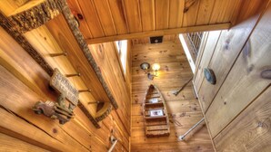 Innenansicht einer Holzhütte mit schrägem Dach, einem kleinen Boot und einer an der Wand befestigten Leuchte.