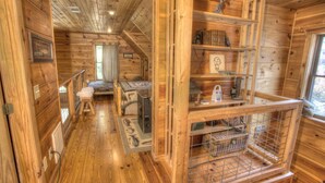 Ein Holzblock-Interieur mit Schlafzimmer im Zwischengeschoss, einer kleinen Küchenzeile und einem Regal mit verschiedenen Gegenständen.