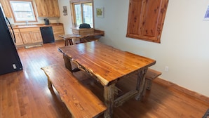 A kitchen with wooden cabinets, a large wooden table, and a bench. - Spacious Lake Barkley Retreat, 7 Queen Beds, Peaceful Cul-de-Sac , Dock Access (Cadiz)