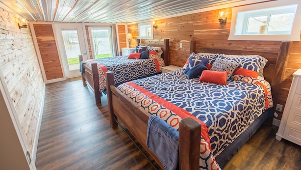 A cozy bedroom with two beds, wooden walls, and a skylight. - Spacious Lake Barkley Retreat, 7 Queen Beds, Peaceful Cul-de-Sac , Dock Access (Cadiz)