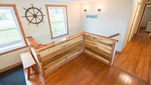 A corner room with wooden flooring, a built-in bench, a ship's wheel decoration, and a window with a view of the outdoors. - Spacious Lake Barkley Retreat, 7 Queen Beds, Peaceful Cul-de-Sac , Dock Access (Cadiz)