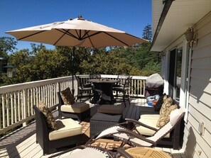 An outdoor patio with wicker furniture, a table, and a large umbrella. - Lake Arrowhead Luxury Escape - Amazing Views For Families, Pets & Remote Workers (Lake Arrowhead)