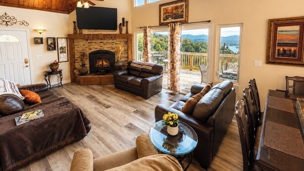 A spacious living room with a fireplace, leather sofas, a television, and a balcony with a view. - Lake Arrowhead Luxury Escape - Amazing Views For Families, Pets & Remote Workers (Lake Arrowhead)