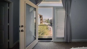 An open door leading to a balcony with a view of buildings and a fence. - Driem House Chic + Legacy Shops Walkable (Plano)
