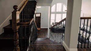 A wooden staircase with a handrail, leading to a landing with a door and a window. - Driem House Chic + Legacy Shops Walkable (Plano)
