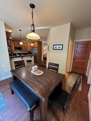 A dining area with a wooden table, benches, and a chandelier.