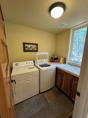 A laundry room with a washing machine, dryer, and a sink with a window view.