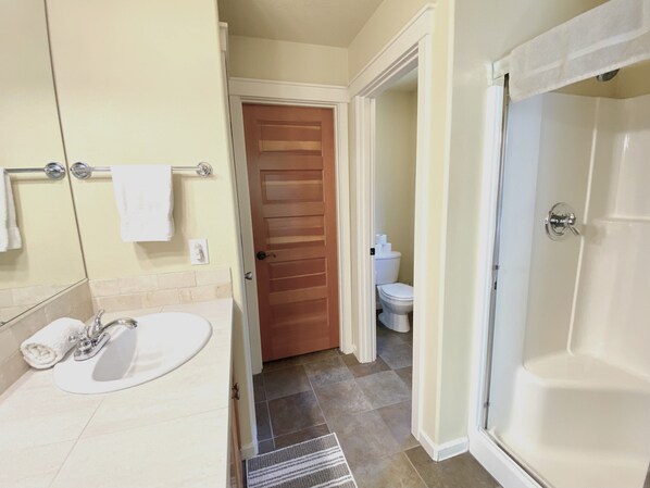 Une salle de bain équipée d’un lavabo, d’un miroir, d’un porte-serviettes et d’un espace douche.
