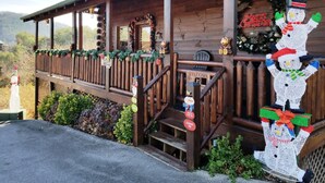 A wooden cabin with a porch decorated for Christmas, including a snowman figure and a 'Merry Christmas' sign. - !BEST LOCATION! RESERVE NOW FOR SPRING BREAK AND SUMMER! BEARFOOT CORNER CABIN!  (Pigeon Forge)