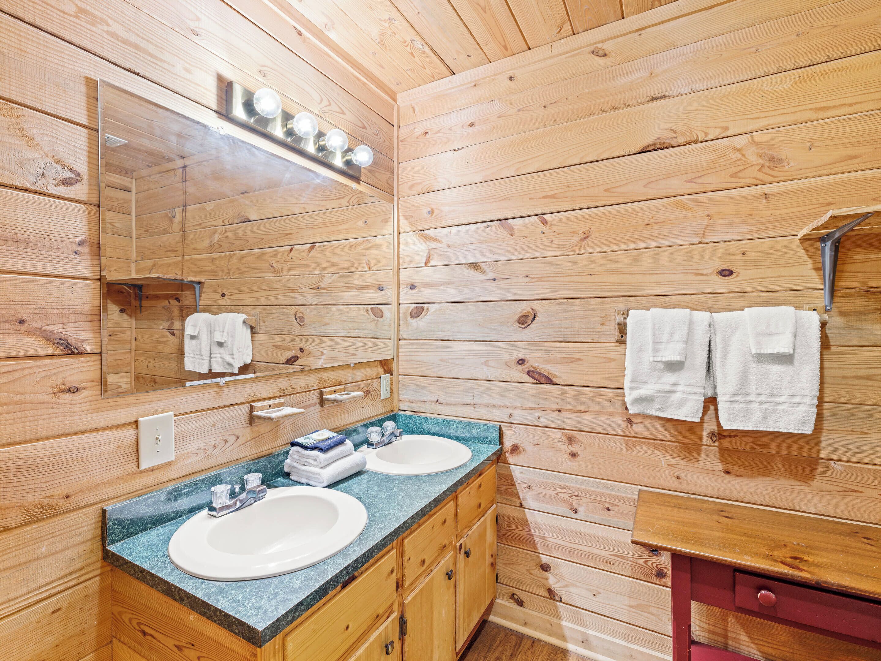 Une salle de bain de style rustique, avec des murs en bois, deux lavabos, un miroir et des armoires en bois.