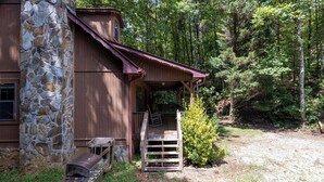 A rustic cabin with a stone foundation, a wooden porch, and a grill outside. - Country Charm D - Cozy Pet Friendly Cabin in Helen (Helen)