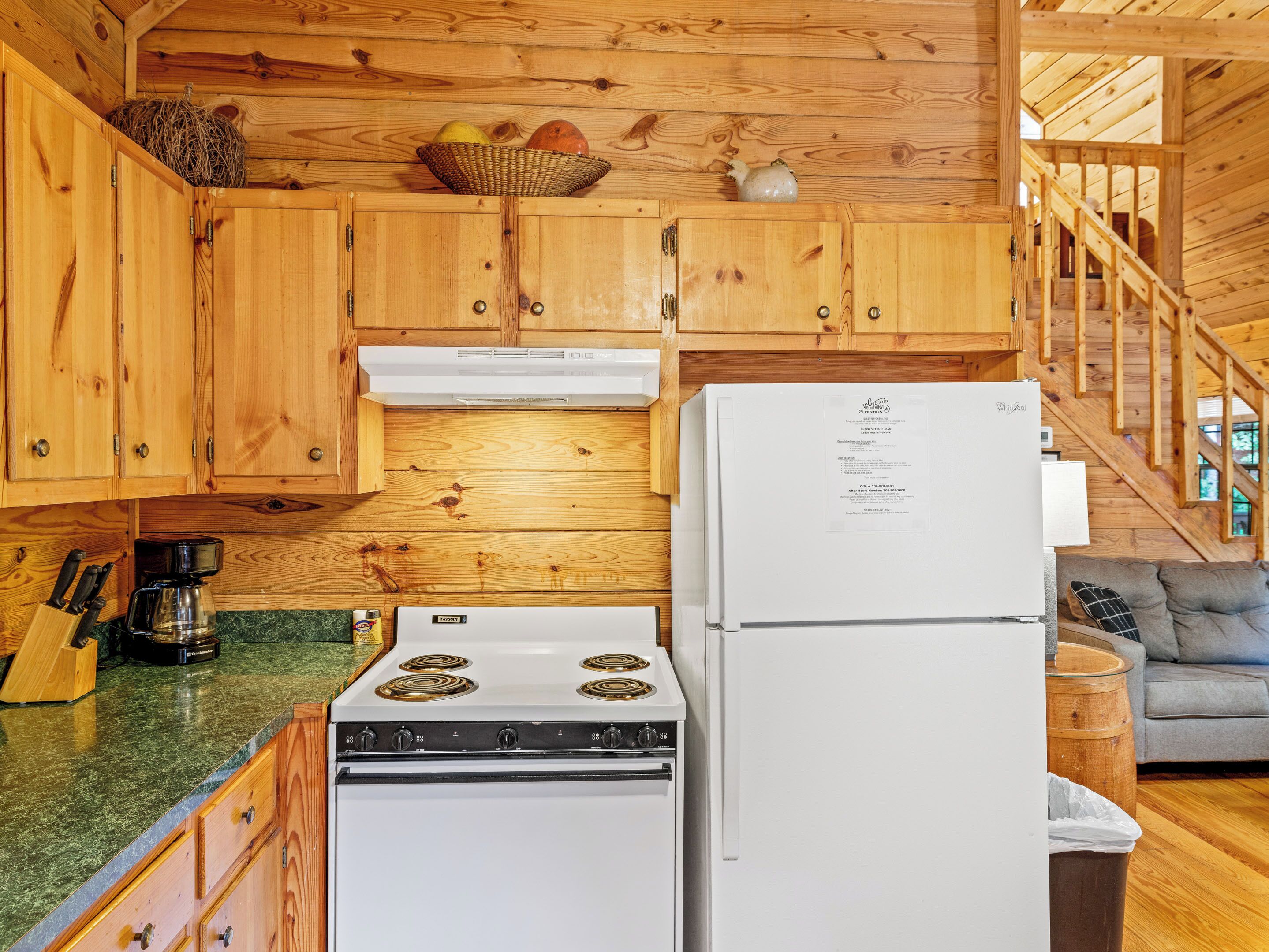 Una cocina con armarios de madera, estufa, refrigerador y cafetera.