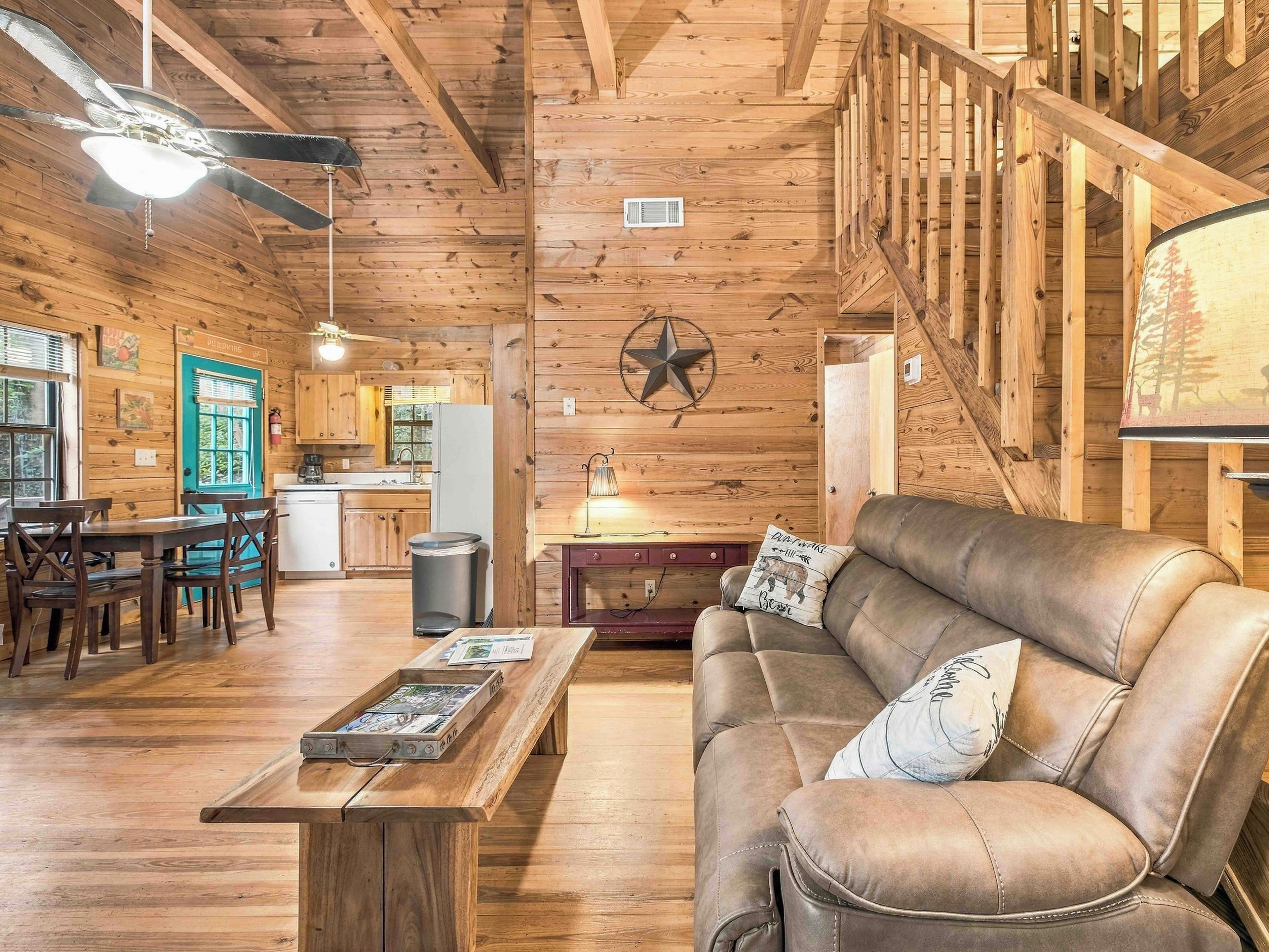 A wooden interior with a sofa, dining table, and kitchen area.