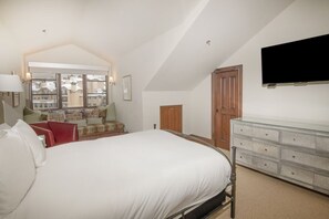 A bedroom with a bed, a dresser, a television mounted on the wall, and a window with a view of buildings. - Charlie's Slopeside: Ski-In/Out Penthouse, Sleeps 12, 3,040 Sq Ft, AC, BC Village, Walk Everywhere (Beaver Creek)